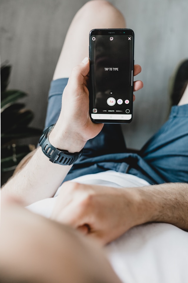 Ein Mann hält sein Handy in der Hand, auf dem der Bildschirm von Instagram Stories "Tap to type" angezeigt wird.
