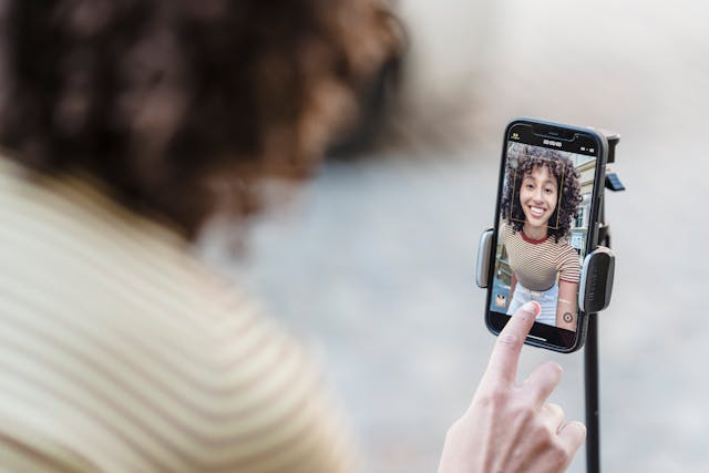 Eine Inhaltserstellerin baut ihr Telefon und ihr Stativ auf, um ein Video von sich selbst aufzunehmen.