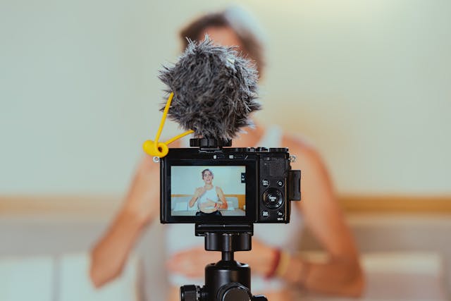 A camera viewfinder showing a female content creator explaining something to her fans on video.