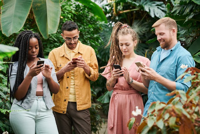 Um grupo diversificado de quatro pessoas a olhar para os seus telemóveis.