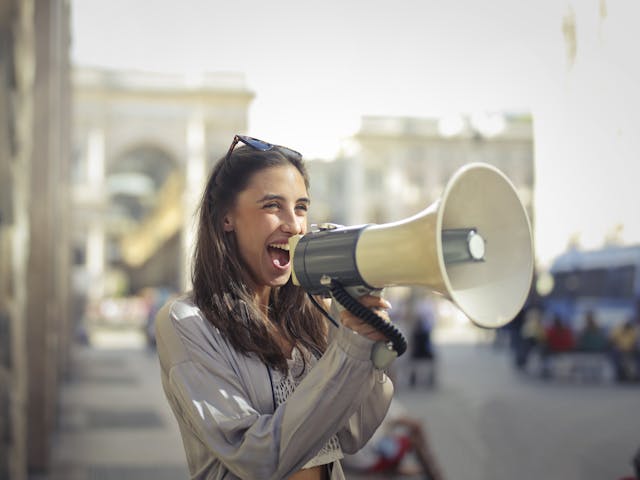 Uma mulher alegre a falar para um megafone para difundir uma mensagem.