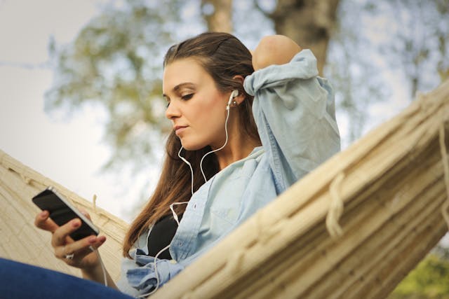 Una mujer mira su teléfono mientras escucha música con sus auriculares.