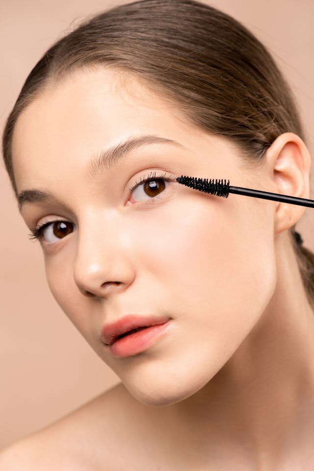Eine Frau mit natürlichem Make-up, die ihre Wimpern mit schwarzer Mascara tuscht.