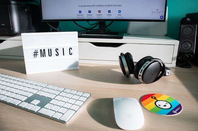 Eine Schreibtafel mit dem Hashtag #Music auf einem Computertisch.