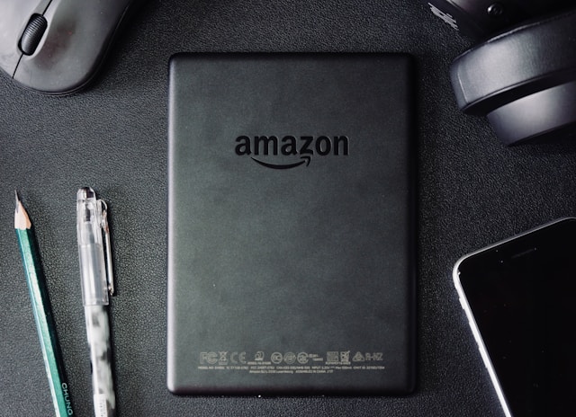 A parte de trás de um Kindle preto, que tem o logótipo da Amazon.