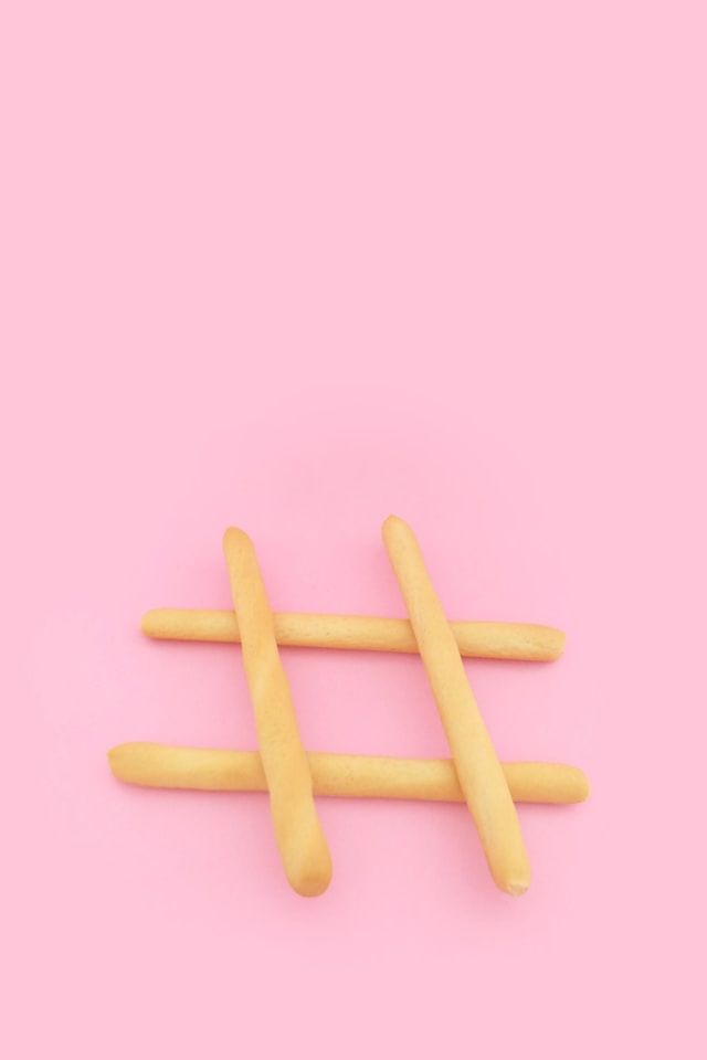 Quatro pãezinhos posicionados para formar o sinal de hashtag num fundo cor-de-rosa.