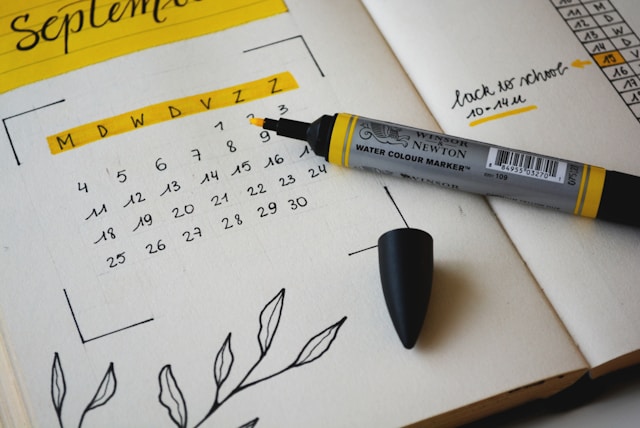 Un calendario mensual escrito a mano en negro y amarillo sobre una agenda.
