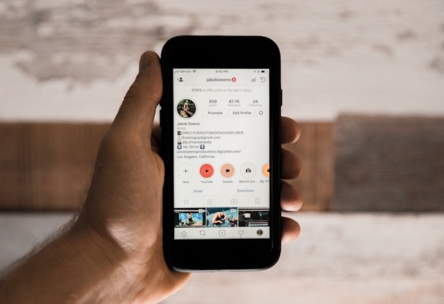 Instagram 에서 남성 인플루언서의 자세한 약력을 표시하는 iPhone을 들고 있는 사람.