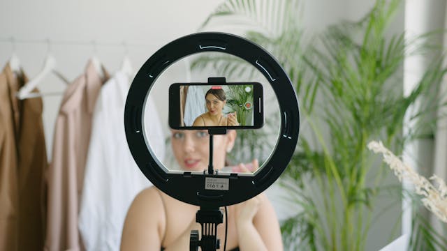 Une micro-influenceuse enregistrant une vidéo d'elle-même avec son smartphone et sa lampe torche.
