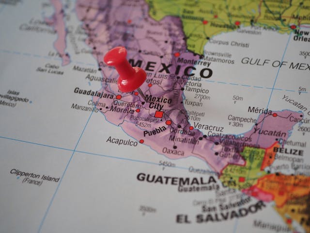 Eine Weltkarte mit einer roten Stecknadel, die Mexiko-Stadt markiert.