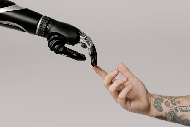 A mão biónica de um robô a tocar as pontas dos dedos de uma mão humana.