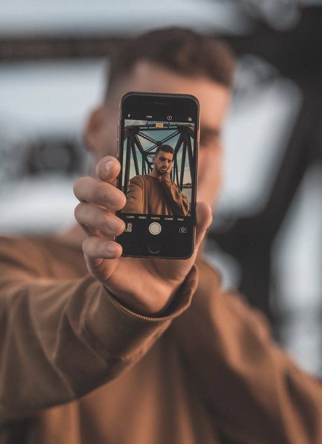 Um homem a tirar uma selfie com o seu iPhone utilizando a câmara traseira.
