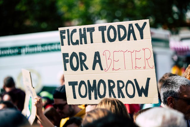 Iemand houdt een kartonnen bord vast bij een protest met de tekst: "Vecht vandaag voor een betere toekomst".