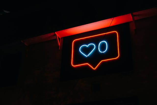 Un letrero de neón azul y rojo que brilla en la oscuridad mostrando cero Instagram likes.
