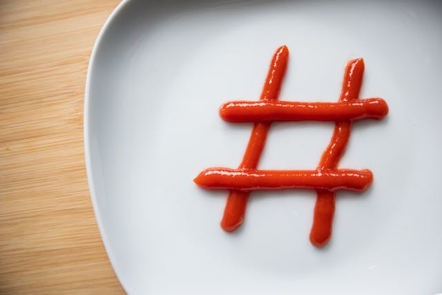 Ein weißer Teller, auf den das Hashtag-Symbol mit Ketchup gezeichnet wurde.
