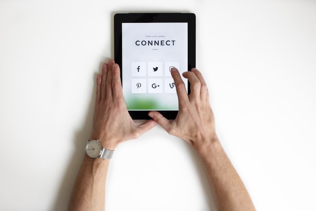 "연결"이라는 단어 아래에 다양한 소셜 미디어 플랫폼이 표시되는 iPad에서 Instagram 아이콘을 탭하는 사람.